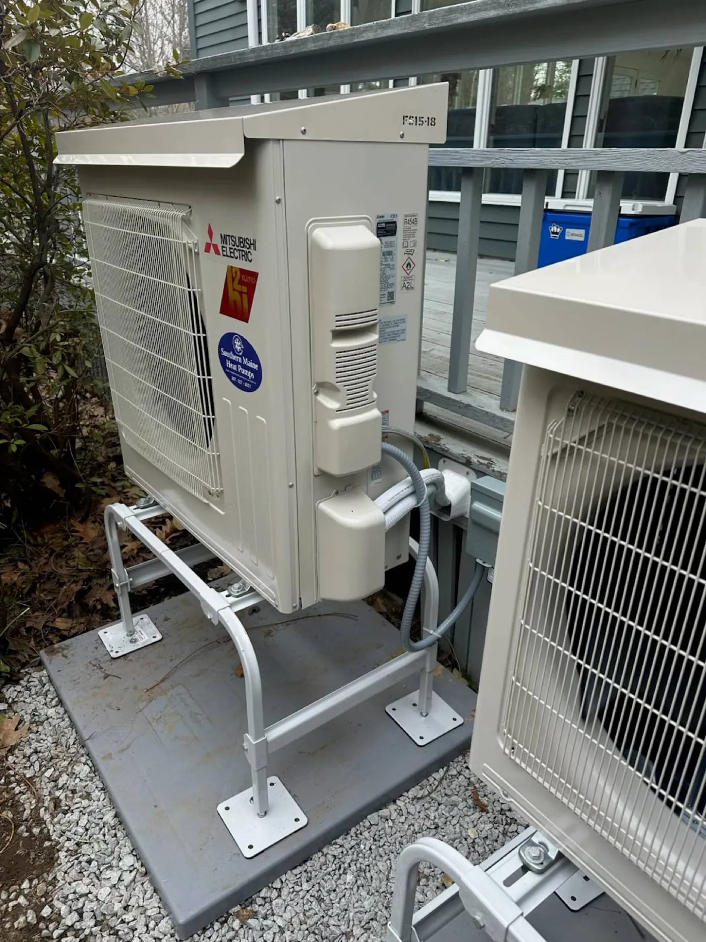 Close-up of outdoor heat pump condenser units mounted on a gravel pad
