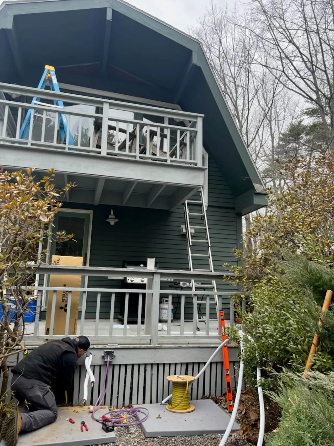 Technician installing an outdoor heat pump condenser unit at a Southern Maine home