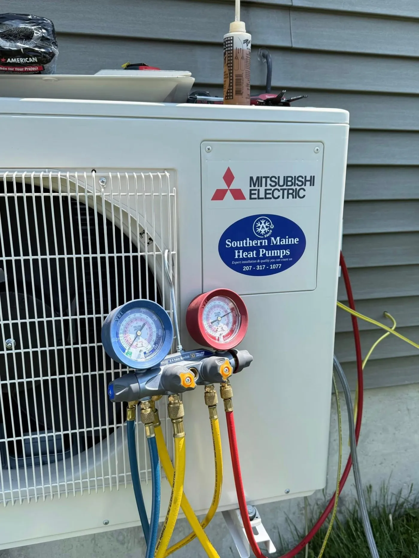 Refrigerant gauge manifold connected to a Mitsubishi outdoor heat pump unit during commissioning