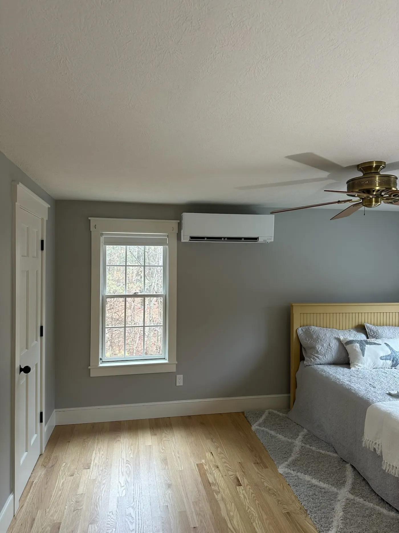Mini-split head unit installed high on a bedroom wall with gray walls