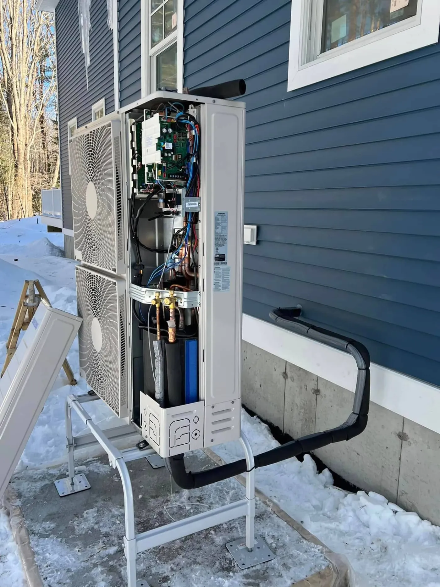 Samsung outdoor multi-zone unit with access panel open, showing the control board and refrigerant lines