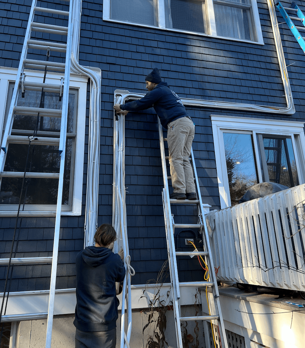 Southern Maine Heat Pumps technicians routing refrigerant line sets during installation
