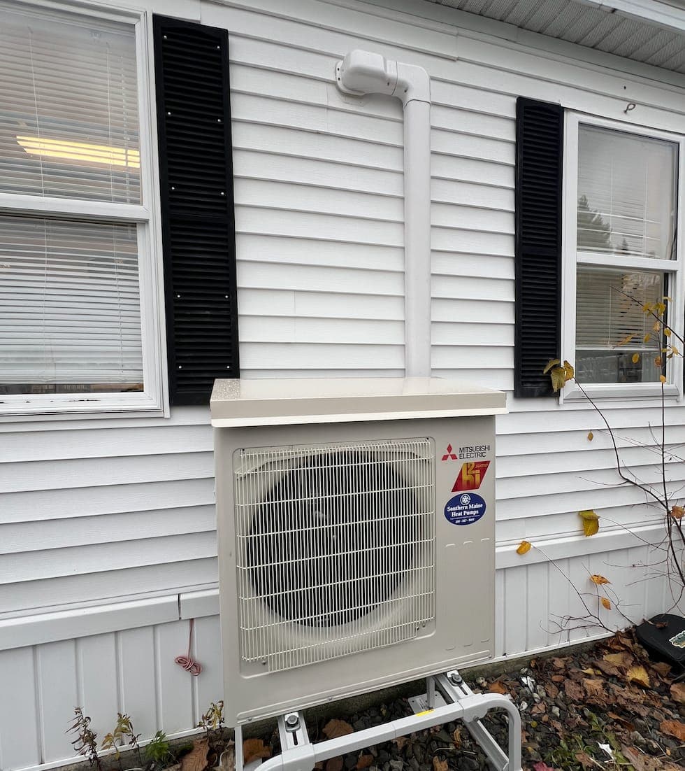 Mitsubishi outdoor heat pump unit installed on the side of a Southern Maine home