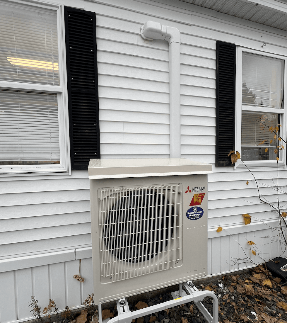 Mitsubishi outdoor heat pump unit installed on the side of a Southern Maine home