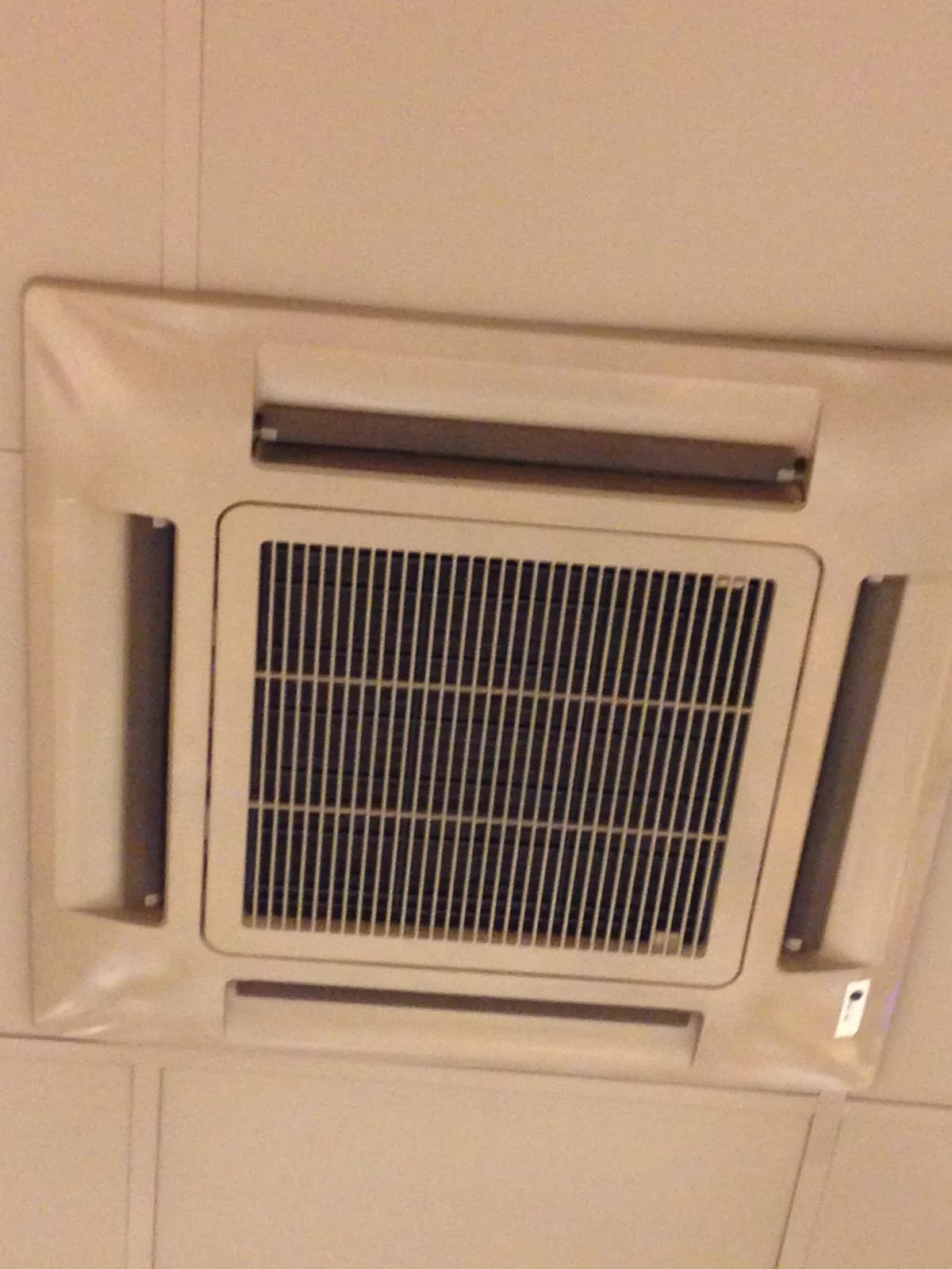 Ceiling cassette-style indoor heat pump unit installed in a commercial ceiling
