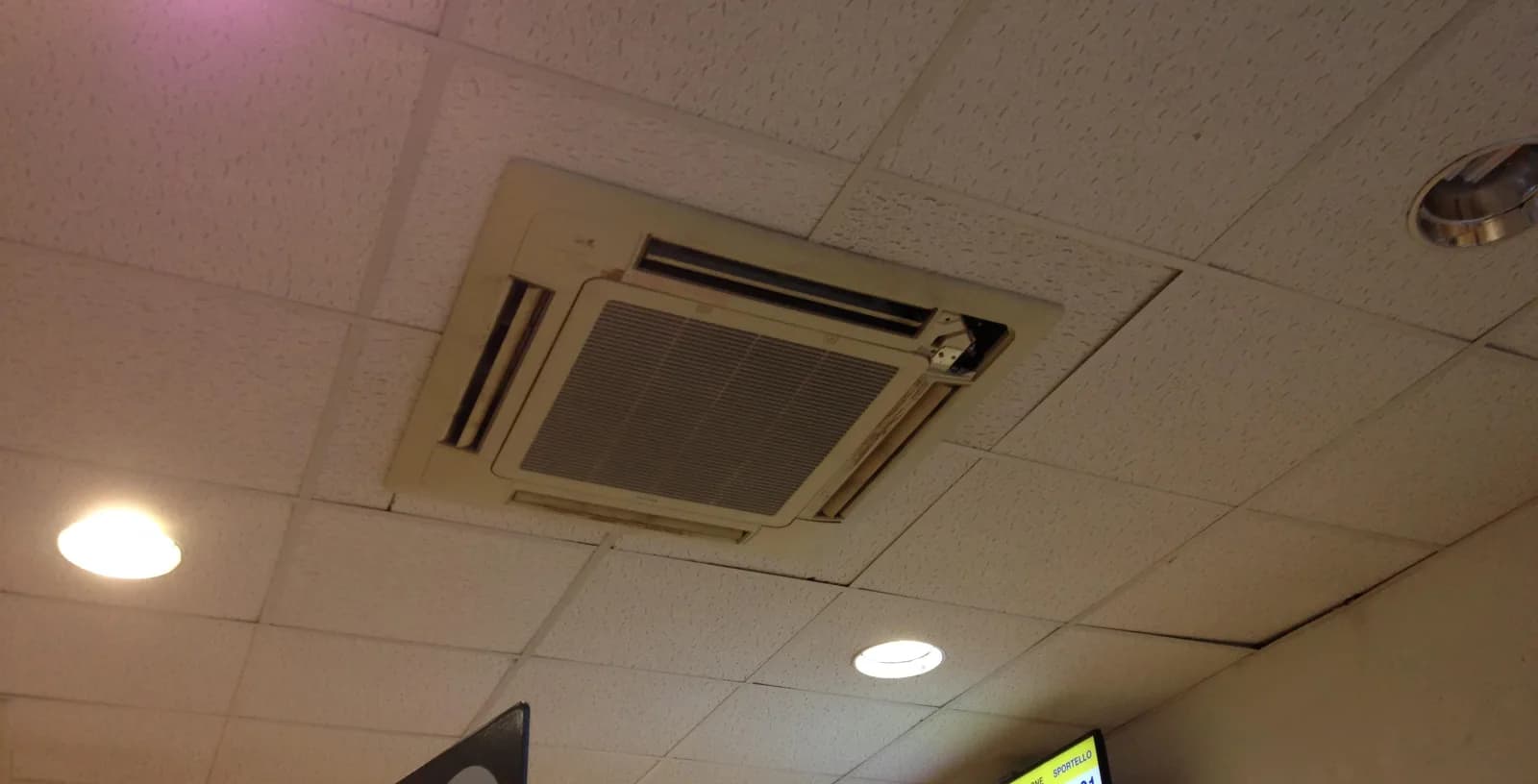 Ceiling cassette-style indoor AC unit installed in a commercial drop ceiling