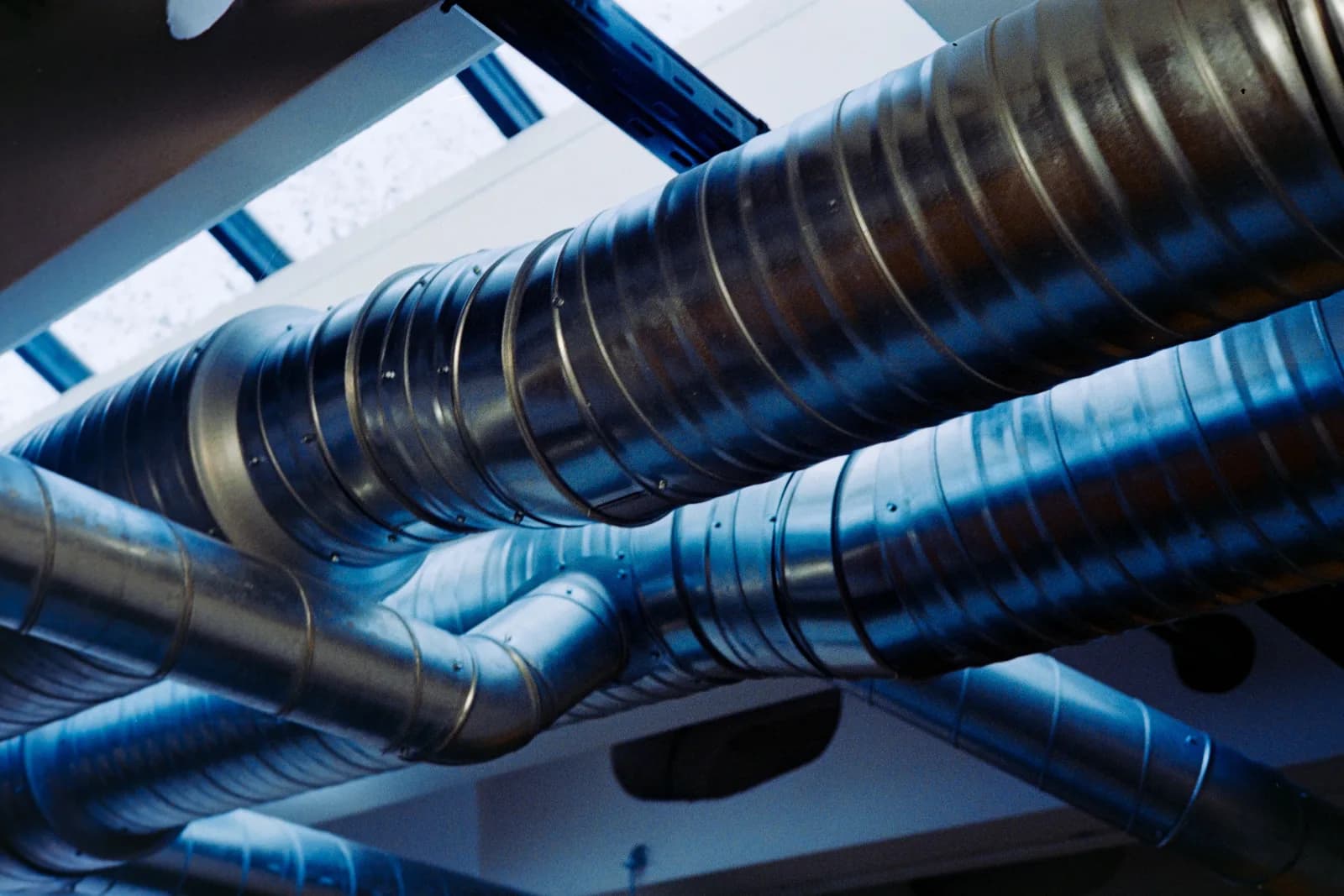 Round spiral ductwork installed overhead in a mechanical room ceiling