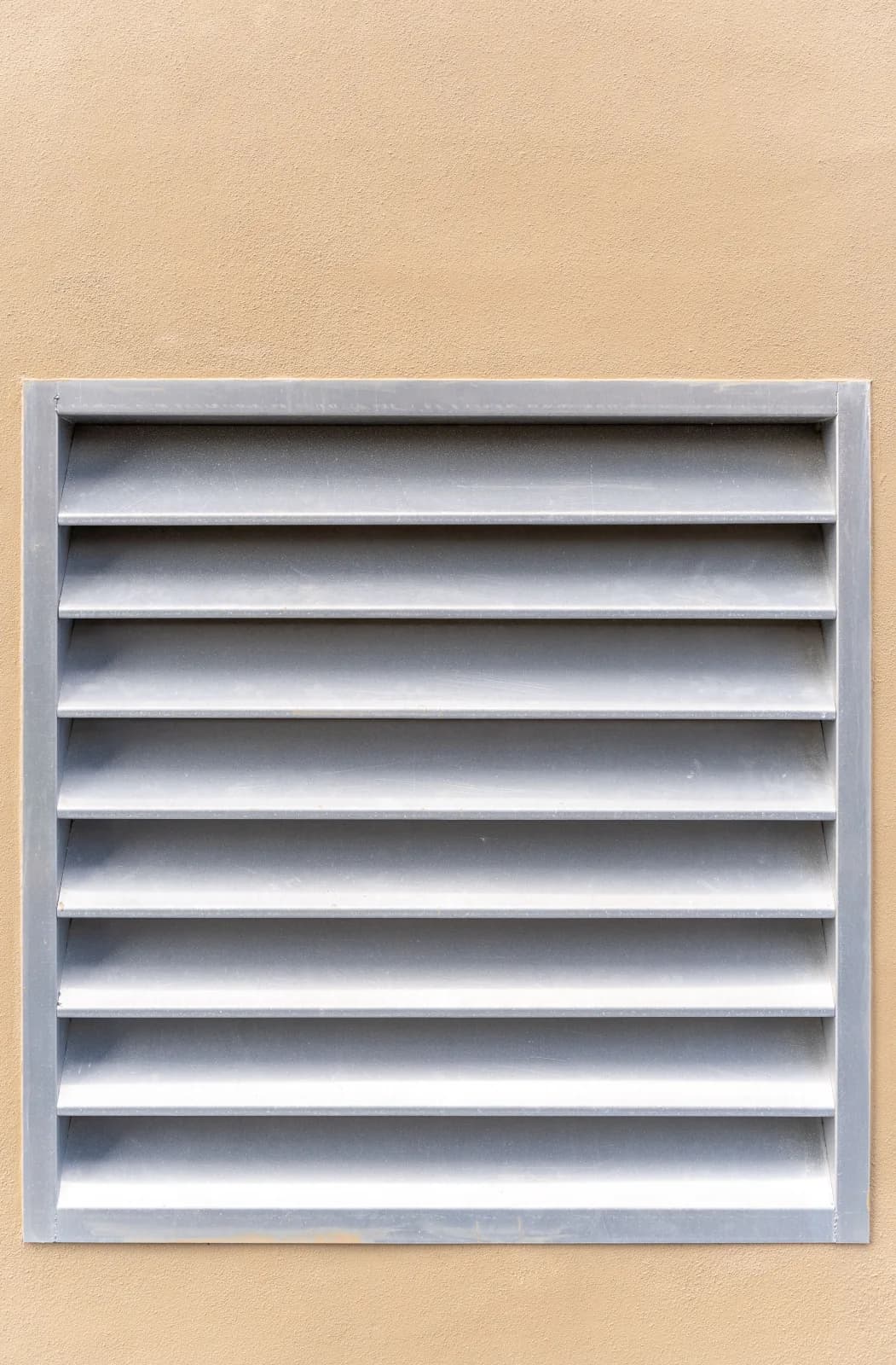 Louvered fresh-air vent set into a stucco exterior wall