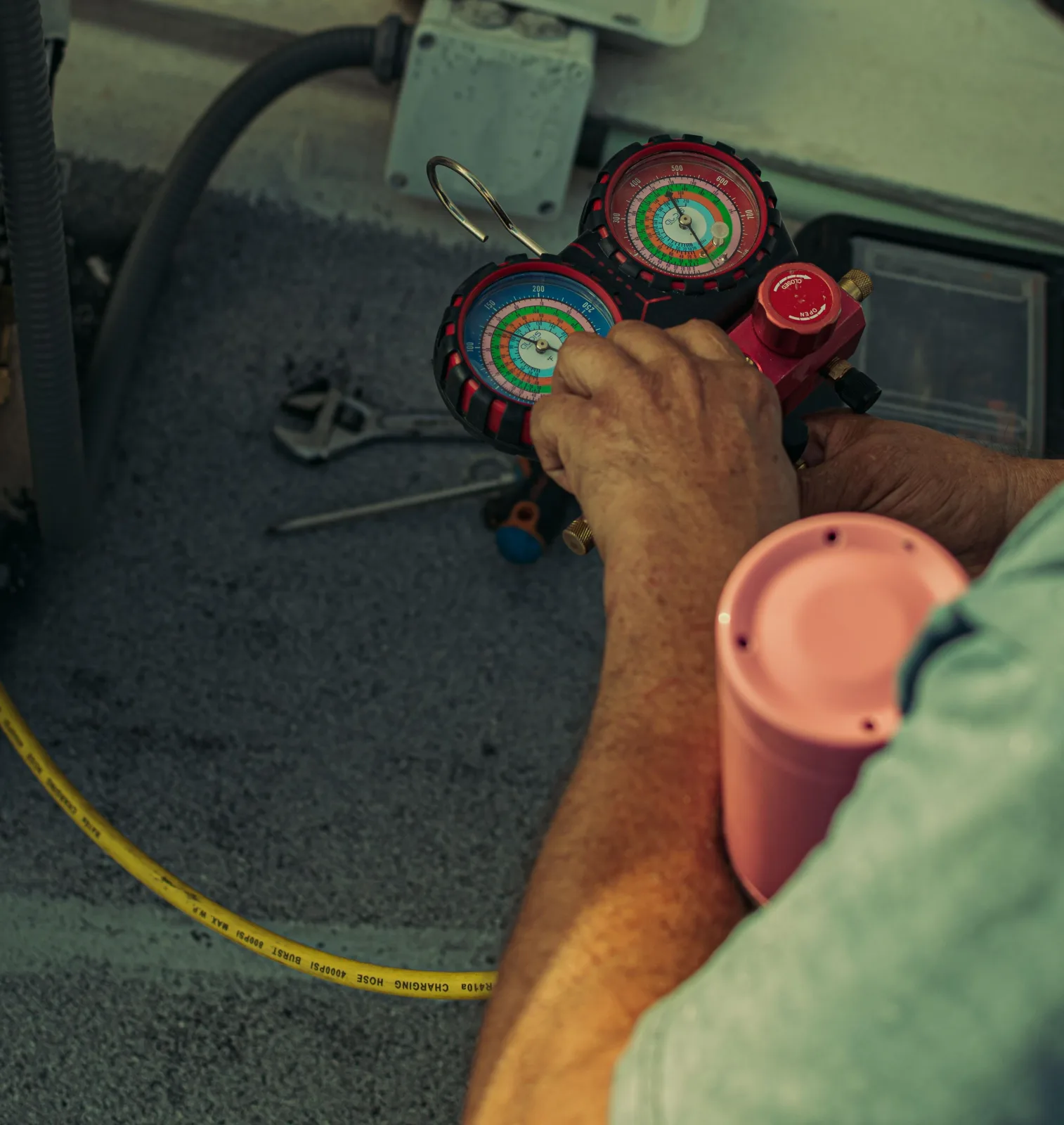 Technician holding a refrigerant gauge manifold connected to an HVAC line set