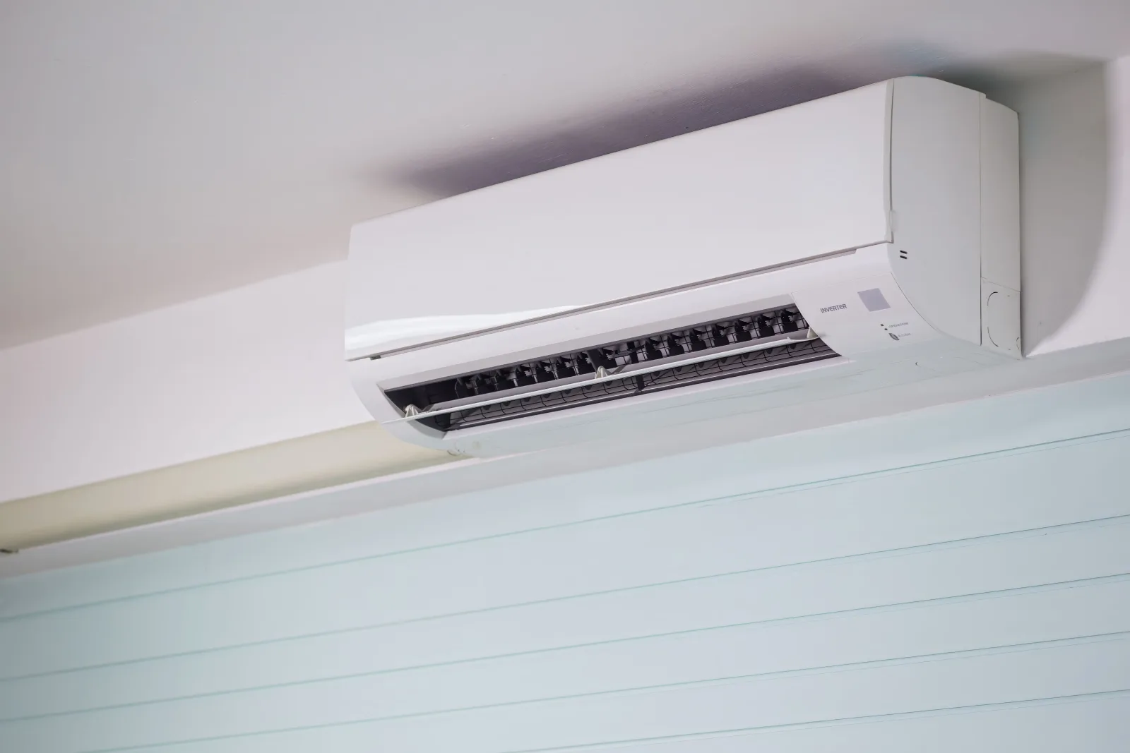 Ductless indoor wall unit mounted near the ceiling of a room